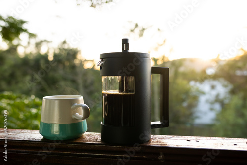 Close up of coffee press and mug of fresh coffee at balcony on sunny day
