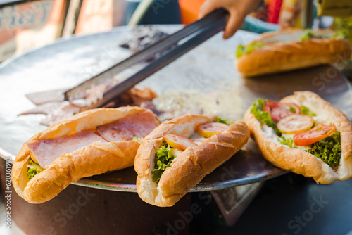 Sandwiches with salad, ham, bacon, egg, cheese, lettuce, tomatoes, tomato sauce and onion on a big pan. Fresh salami sandwich at vang vieng. Image of healthy food.