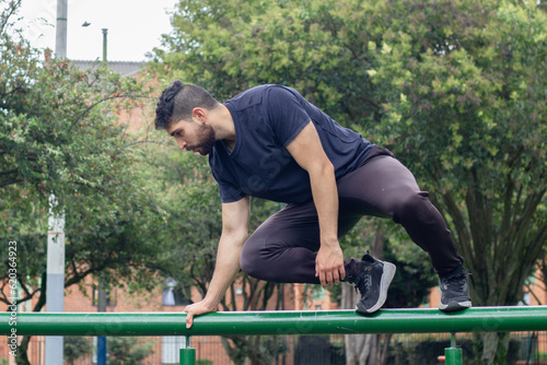 young man training and doing parkour in a city park