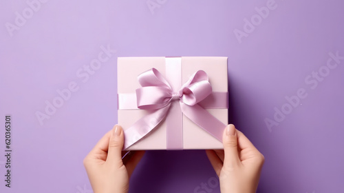 Female hands holding a purple gift box with a bow. © tashechka