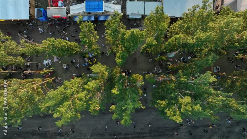 Crowd of fans are cheering at open-air music festival, back view. A large crowd of people at a music festival near the scene in the evening in the summer. Concert in the open air.Aerial view in nature Crowd of fans are cheering at open-air music festival, back view. A large crowd of people at a music festival near the scene in the evening in the summer. Concert in the open air.Aerial view in nature