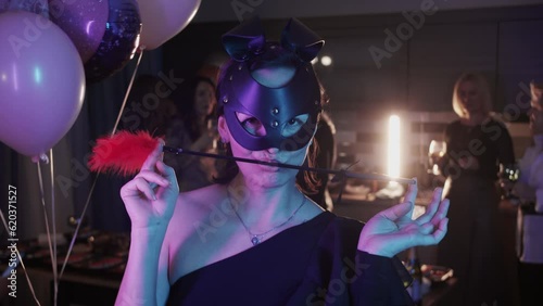 Portrait of woman in mask playing feather tickler