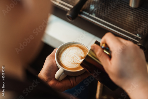 Top view, Barista pouring milk foam to making latte art coffee. Young man barista working at coffee shop. Latte art menu coffee, Espresso, Coffee menu making concept. Selective focus.