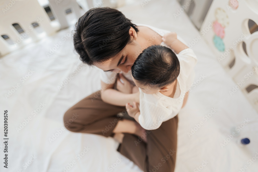 Top view, Asian mother embracing adorable her son at home. Asian mom nurturing love newborn baby. Happy asian family healthcare love together mother’s day concept. Top view, Asian mother embracing adorable her son at home. Asian mom nurturing love newborn baby. Happy asian family healthcare love together mother’s day concept.