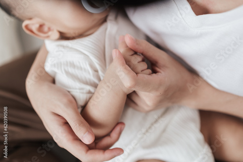 Top view, Adorable hand of baby and mother. Baby sleeping on hand. Mom nurturing love newborn baby. Mom nursing baby. Happy asian family healthcare love together mother’s day concept.