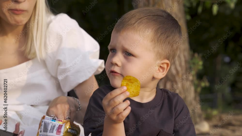 Close-up of a Child. Eating Chips. Enjoying Sunset on the Beach Close-up of a Child. Eating Chips. Enjoying Sunset on the Beach