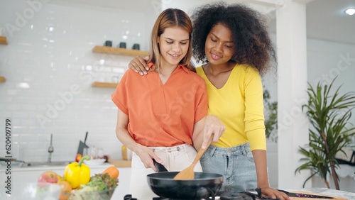 LGBT lifestyle. Multiracial lesbian woman happily preparing food together. Lesbian women couple embracing and spending time together in kitchen room. Lesbian couple