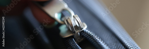 Female hand opening black brass zipper of suitcase
