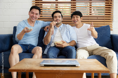 group of men watching tv and eating popcorn in living room
