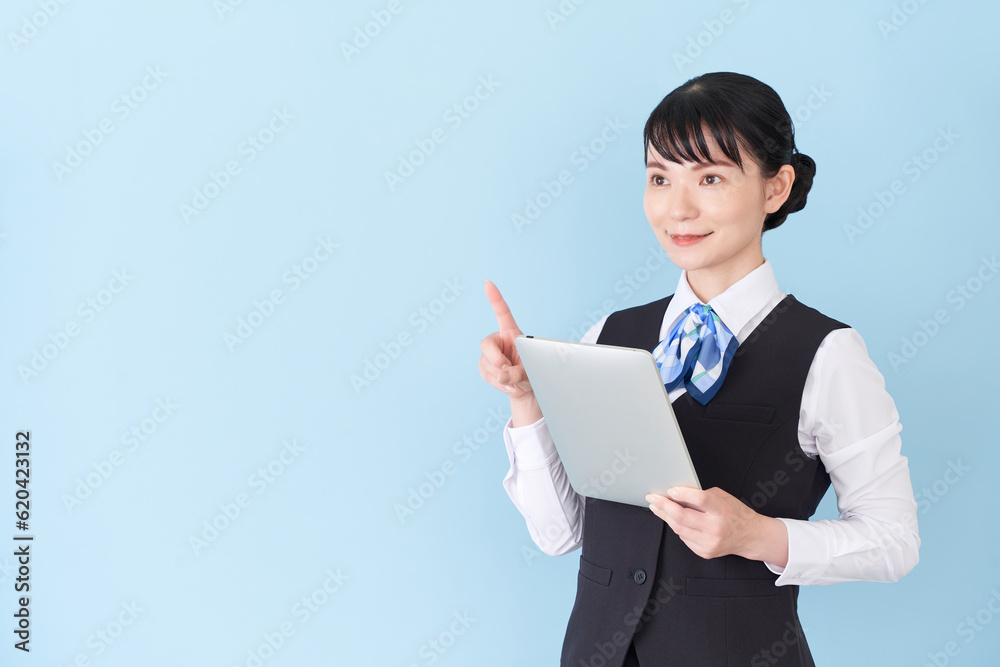 タブレットを操作するベストにリボンタイの制服を着た、受付業務、事務業務の女性 タブレットを操作するベストにリボンタイの制服を着た、受付業務、事務業務の女性
