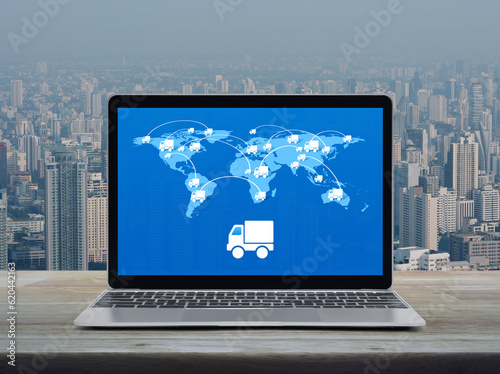 Delivery truck icon with connection line and world map on modern laptop computer screen on table over city tower, Business transportation online, Elements of this image furnished by NASA