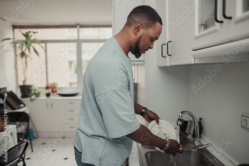 African man washing the dishes at home