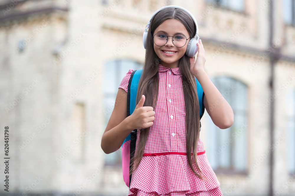 teen girl has education online in headphones, thumb up. teen girl has education online