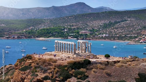 The ancient Temple of Poseidon at the bay of Cape Sounion at the edge of Attica, Greece, during summer time photo