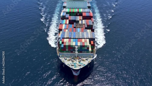 Aerial tracking of a large container cargo vessel traveling with speed over blue ocean