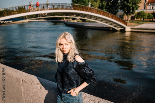 beautiful young cheerful girl on the street of the city, the blonde is resting outdoors