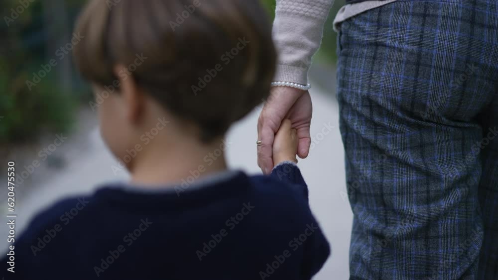 Parent holds the hand of a little child. Trust family concept. Mother holding hands with son walking together outdoors in motion Parent holds the hand of a little child. Trust family concept. Mother holding hands with son walking together outdoors in motion