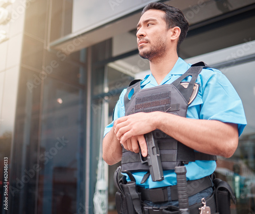 Security guard, safety officer and bodyguard man with a gun outdoor to patrol, safeguard and watch. Serious asian male at a building or property for crime prevention or armed response with a weapon