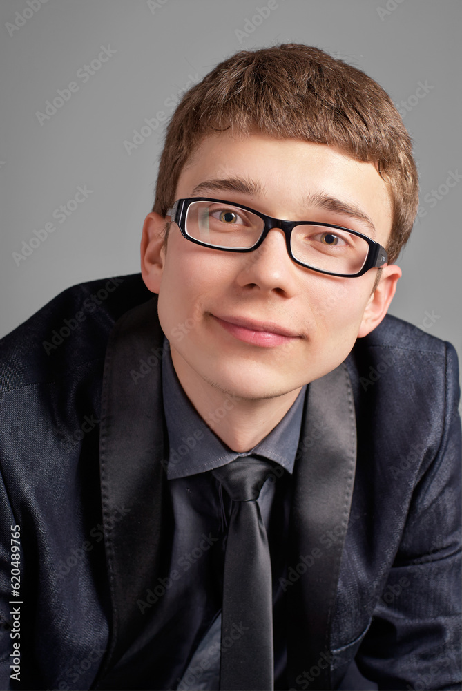 Young man with glasses smiling on grey background