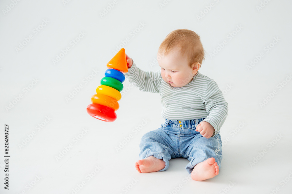 charming baby in a T-shirt and jeans is playing with toy pyramid, a postcard, a banner, a place for text. High quality photo charming baby in a T-shirt and jeans is playing with toy pyramid, a postcard, a banner, a place for text. High quality photo