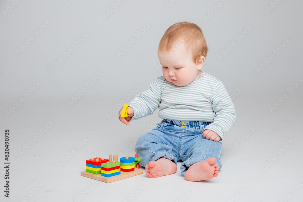charming baby in a T-shirt and jeans is playing with toys, a postcard, a banner, a place for text. High quality photo charming baby in a T-shirt and jeans is playing with toys, a postcard, a banner, a place for text. High quality photo