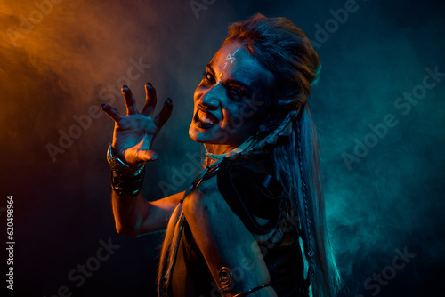 Profile photo of merciless furious valkyrie woman grin teeth arm scare orange blue lights isolated on dark background