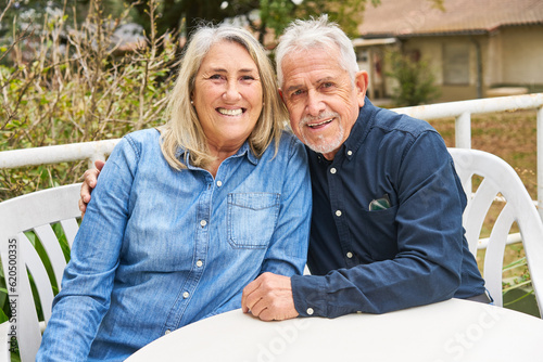 Cheerful senior couple sitting at table in garden