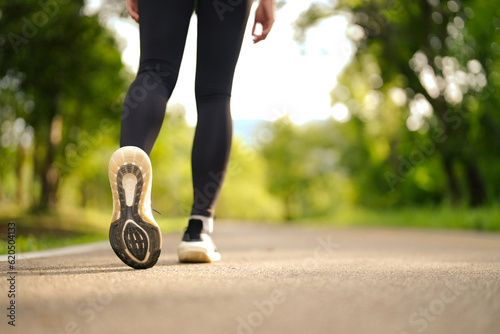 Sporty woman running and jogging in the park. Close up picture of running shoes on a path in the park. © Somkiat