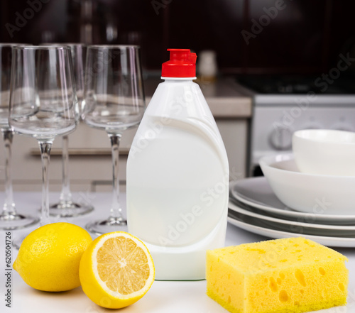 Detergent with lemon and sponge on the table in the kitchen. Cleaning concept. Mockup. Close-up. Selective focus.