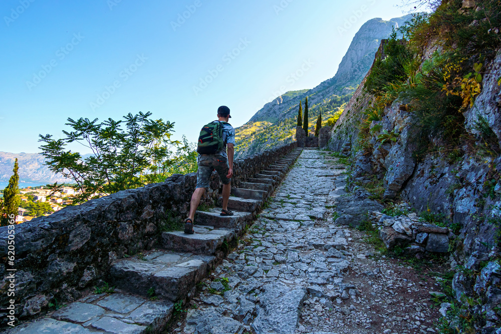 a tourist walks along the fortress walls, view of the old town of Kotor in Montenegro, medieval architecture, travel