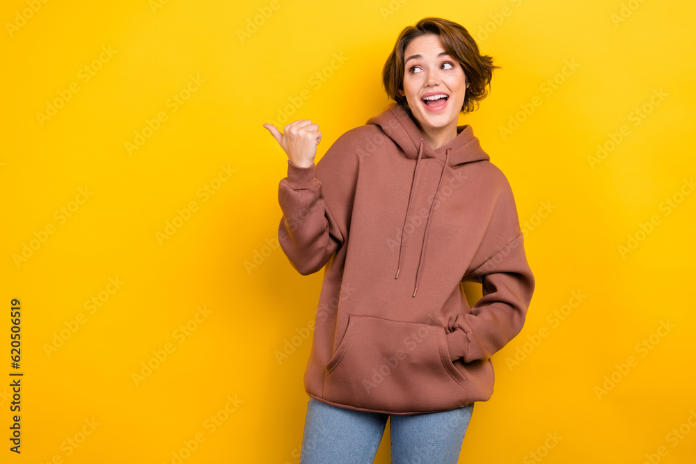 Photo of impressed astonished funky woman wear brown hoodie staring directing at offer empty space isolated on yellow color background Photo of impressed astonished funky woman wear brown hoodie staring directing at offer empty space isolated on yellow color background