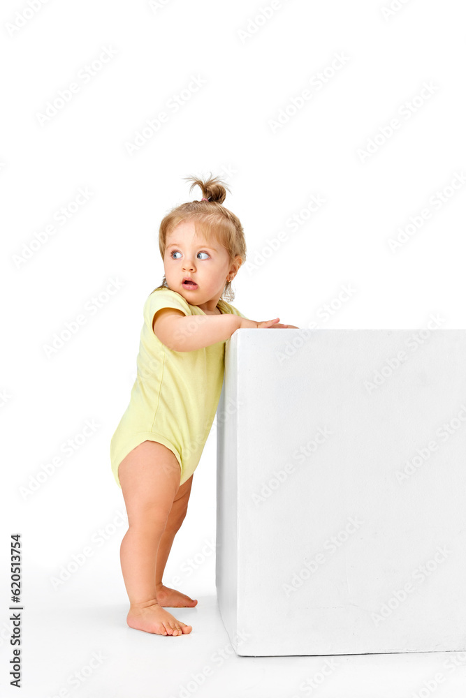 Attentive look. Full-length portrait of beautiful, funny, cute little baby girl child standing against white studio background Attentive look. Full-length portrait of beautiful, funny, cute little baby girl child standing against white studio background