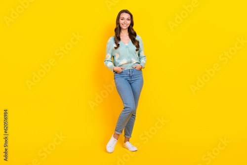 Full size photo of satisfied glad young girl put arms pockets posing isolated on yellow color background