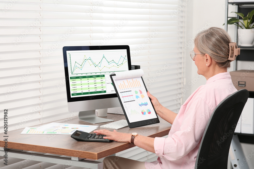 Senior accountant working at wooden desk in office Senior accountant working at wooden desk in office
