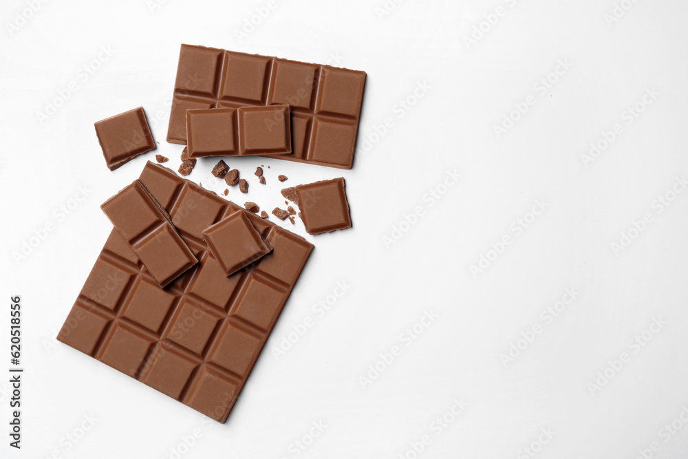Delicious broken chocolate bar on white background, flat lay. Space for text Delicious broken chocolate bar on white background, flat lay. Space for text