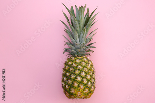 Whole ripe pineapple on pink background, top view