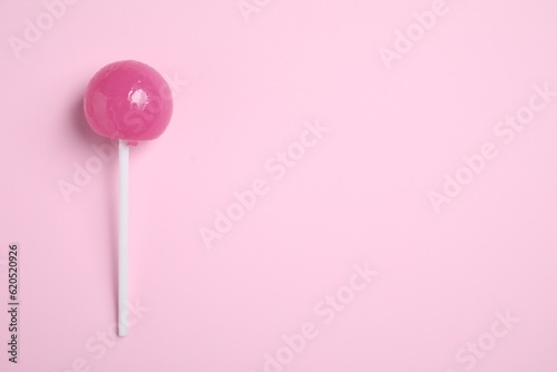 Stick with bright lollipop on pink background, top view. Space for text