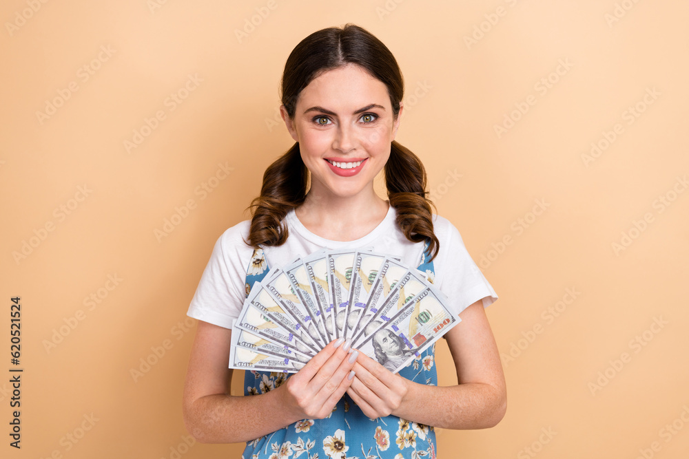 Photo of shiny adorable lady wear flower print dress holding money cash fan isolated beige color background Photo of shiny adorable lady wear flower print dress holding money cash fan isolated beige color background