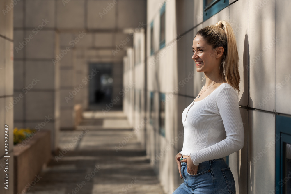Portrait of a beautiful girl standing outside in urban area and smiling.