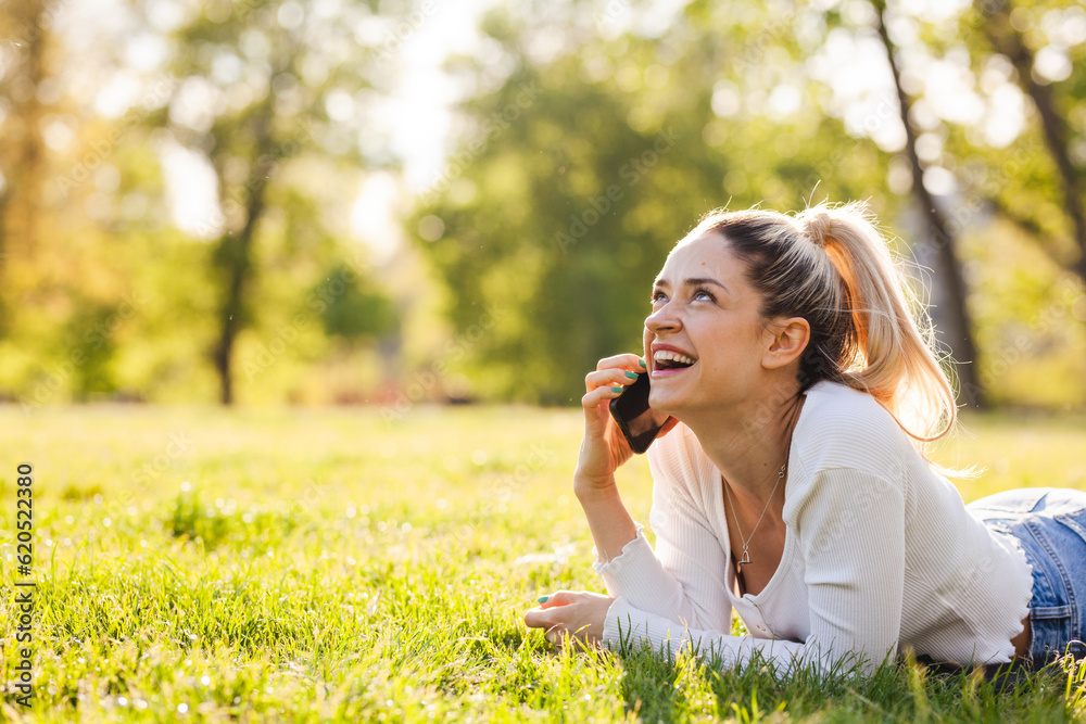 Beautiful girl lying in a field in the park. Talking on phone. Beautiful girl lying in a field in the park. Talking on phone.