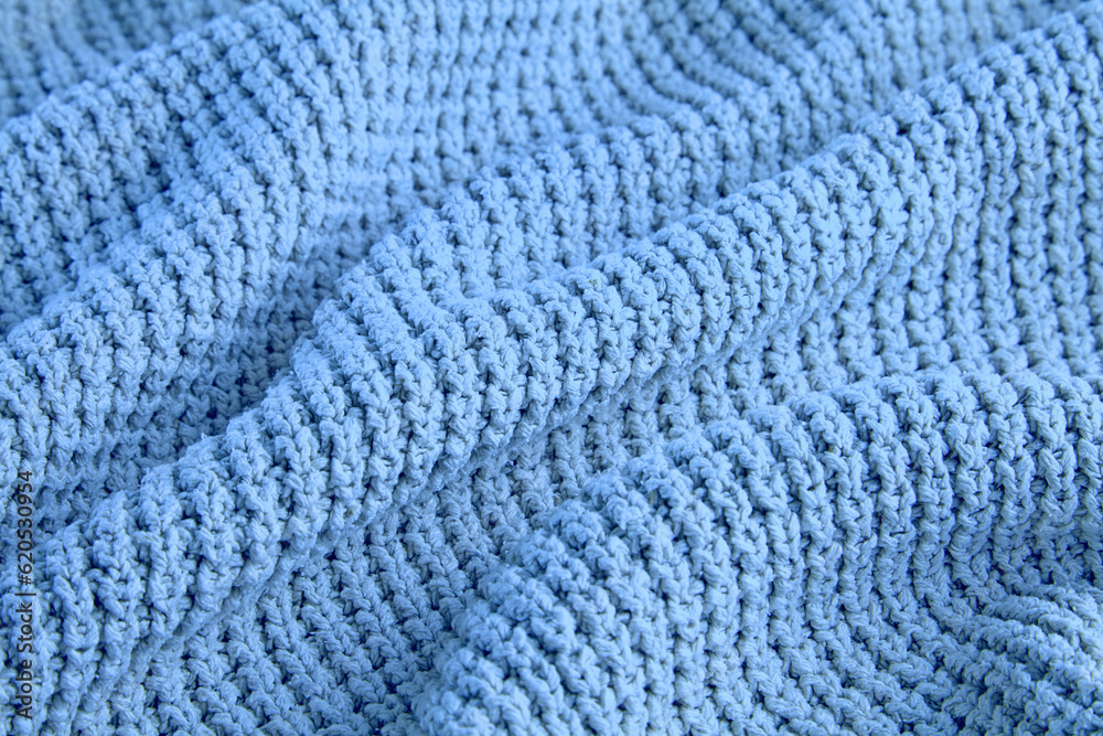 blue knitted clothes of coarse knit with folds and shadows as a background for design blue knitted clothes of coarse knit with folds and shadows as a background for design