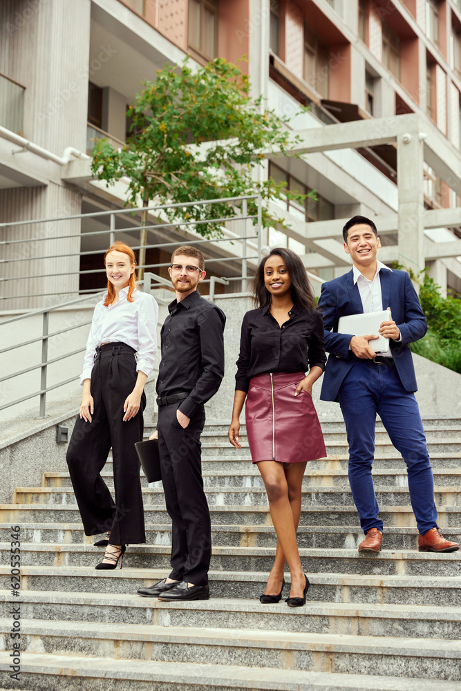 Fototapeta premium Young people, employees, managers standing in office and smiling, City, street background. Success and promotion