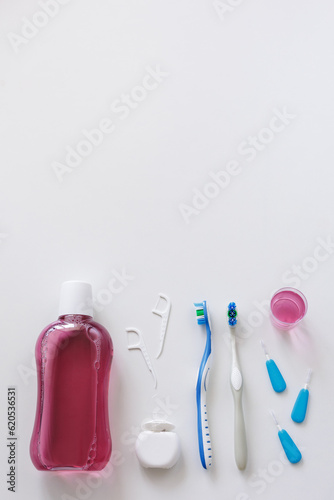 Flatlay of dental floss, toothbrushes, toothpicks and rinse on white with copyspace