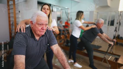 Senior Man Exercising in Guided Workout, Pilates Studio Session with Female Coach, elderly person using machine to stretch, taking care of spine health