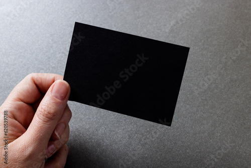 Hand of caucasian woman holding black business card with copy space on grey background
