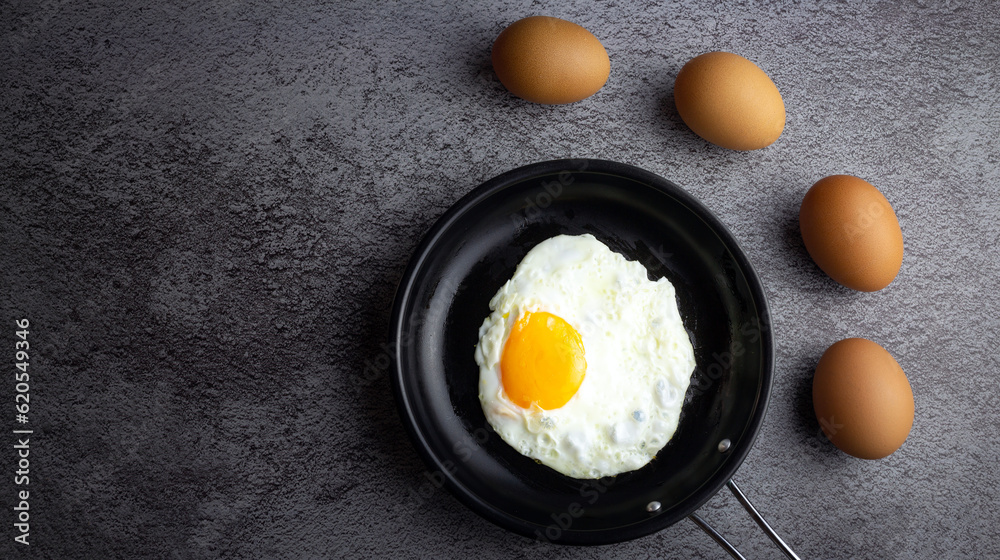 Top view of Breakfast menu fried eggs in an iron pan and raw chicken eggs. Top view of Breakfast menu fried eggs in an iron pan and raw chicken eggs.