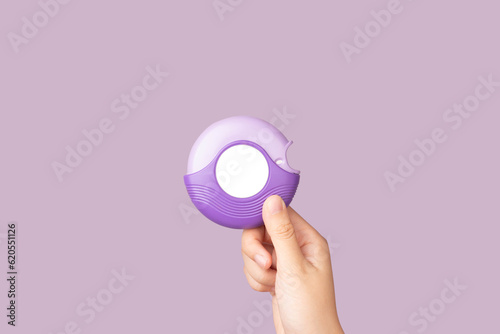 Asthma and COPD concept. Hand holding medicine dry powder inhaler on violet background. Pharmaceutical product is used to lung inflammation and prevent asthma attack. photo