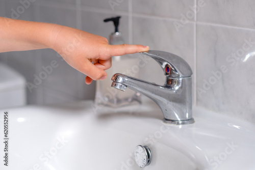 The child turn off the water tap after hygienic procedures. The concept save water and protect the environment.  photo