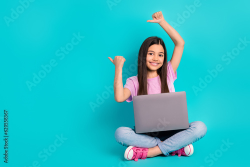 Full length body photo of cute schoolgirl wear pink t-shirt direct fingers empty space it course for kids isolated on cyan color background