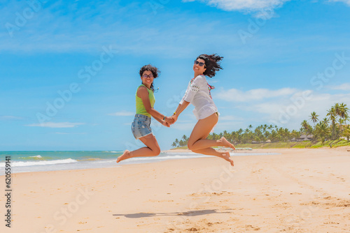 Mãe e filha pulando na areia da praia